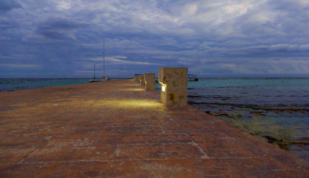 Stone pier on the shore of the warm tropical sea. After sunset, at dusk.