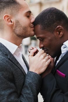 close up portrait of afro american guy kissing caucasian boy hands. Concept of same sex couple, gays and lgbt proposal