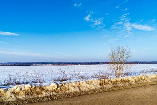 The road, not yet melted snow in the early spring in the suburbs.