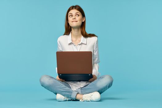 woman with laptop learning internet online education blue background. High quality photo