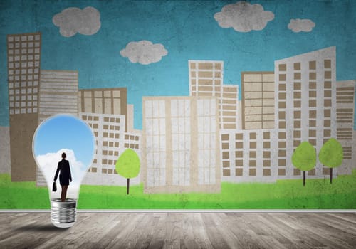Businesswoman inside light bulb against city drawn concept