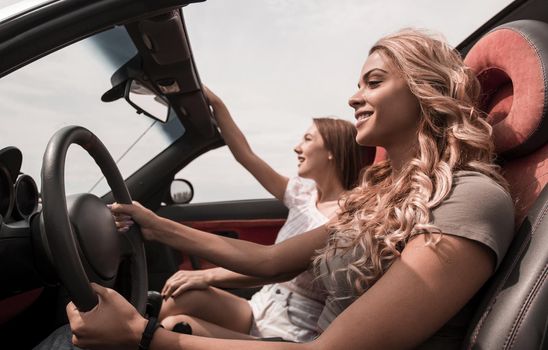 side view.two happy girls riding in the car.leisure, travel and people