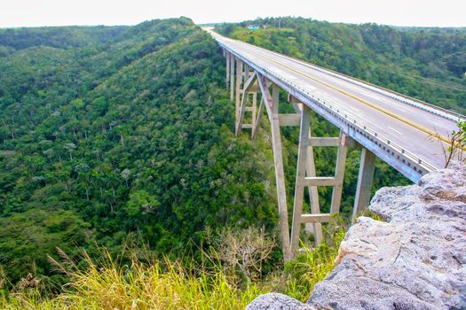 Beautiful arched bridge over a deep gorge, among dense tropical vegetation. Republic of Cuba