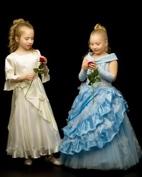 Two adorable princess girls with flowers on a black background. Concepts style and fashion.