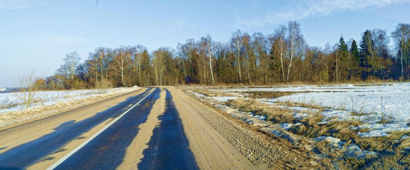 Panorama. Asphalt road stretching away near the forest. In early spring in Russia.