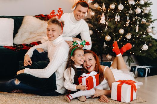 Happy family near the Christmas tree with gifts.