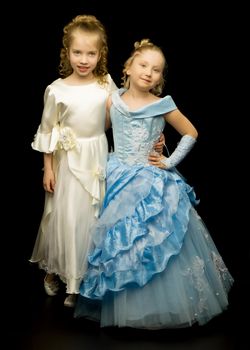 Two cute little girls in full growth, in the studio on a white background. The concept of a happy childhood, Beauty and fashion. Isolated.