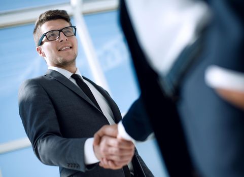 Confident young businessmen smiling and shaking hands bottom view.