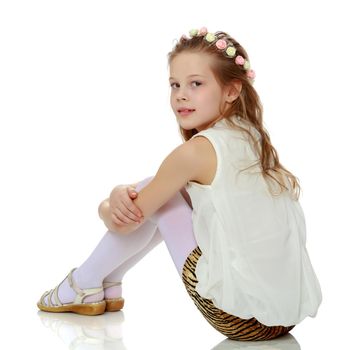 Cute girl posing on the floor in the studio. Hugs his knees. Isolated on white background. The concept of beauty and fashion