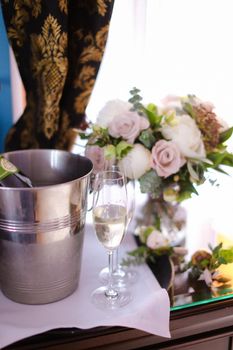 Bucket with champagne, wineglass and flowers on table. Concept of decorations for celebrating wedding.