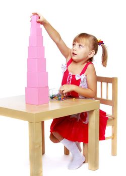 Cute little girl in Montessori in kindergarten working with a pink pyramid.