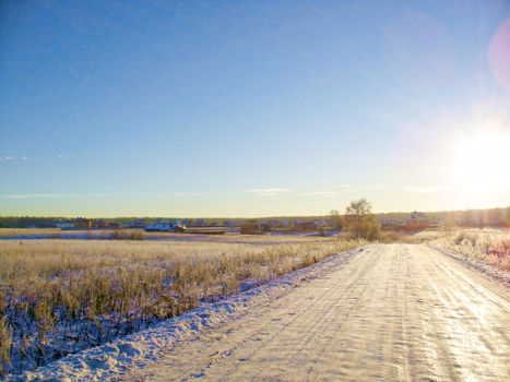 The snow-covered road is an early, sunny, frosty morning in the suburbs.