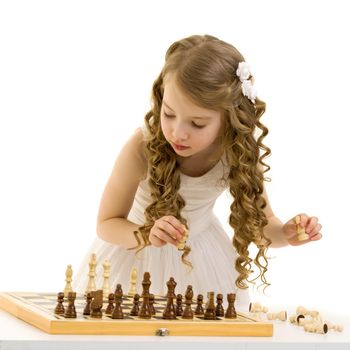 A little girl is playing chess. The concept of creative education of a child, training of thinking. Isolated on white background