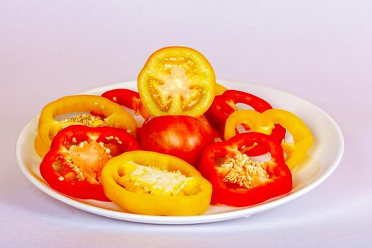 Bulgarian pepper red and sliced yellow lies on a white plate. The concept of a healthy diet.