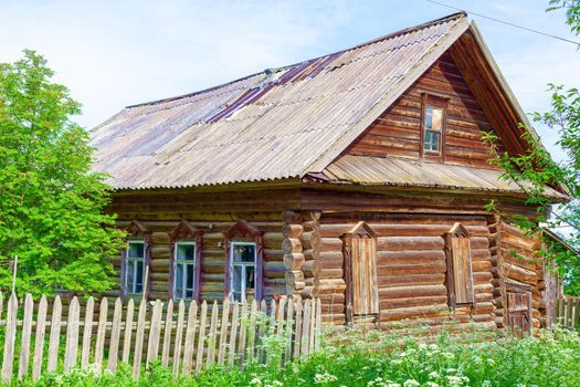 Old log house among dense trees in a village on the edge of Russia. A picturesque place for tourism.