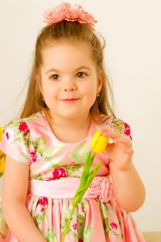 A cute little girl with a bouquet of tulips, in the spring in the studio. The concept of the awakening of nature after winter, the expectation of summer.