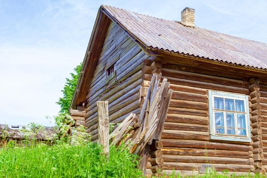 Old log house among dense trees in a village on the edge of Russia. A picturesque place for tourism.