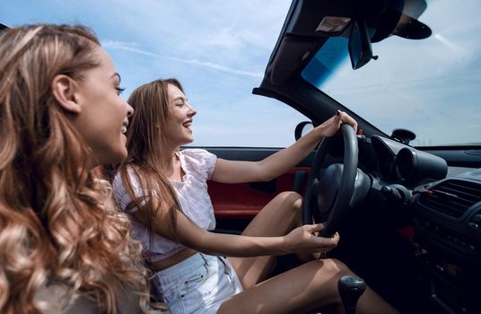 smiling girlfriends traveling in a convertible car.leisure, travel, travel and people