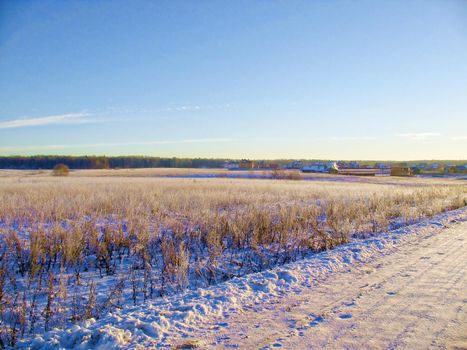 The snow-covered road is an early, sunny, frosty morning in the suburbs.