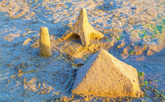 Beautiful sand castle illuminated by the morning sun on the beach of the tropical sea. The concept of a family vacation at sea.