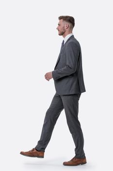 side view. the young businessman confidently steps forward .isolated on white background