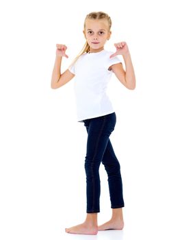 A beautiful little girl in an empty white T-shirt points to herself. The concept of design of T-shirts, advertising of children's goods. Isolated on white background.