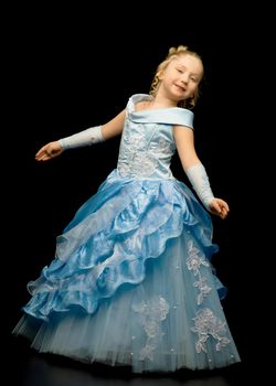 Beautiful little girl in a long, elegant dress. Studio Princess on a black background. Concepts and trendy form for a magazine cover.