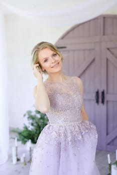 Beautiful bride standing near wooden gate and wearing dress. Concept of wedding and fiancee photo session.