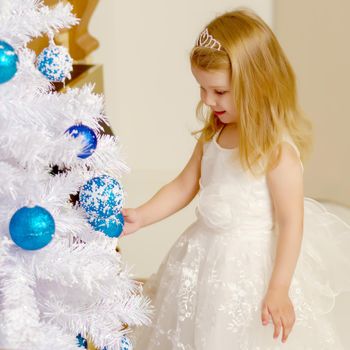 A happy little girl is decorating a Christmas tree. The concept of holidays, Christmas and New Year. Isolated on white background.