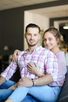 Young cute nice girl hugging boyfriend indoors and smiling. Concept of happy couple, relationship and love.