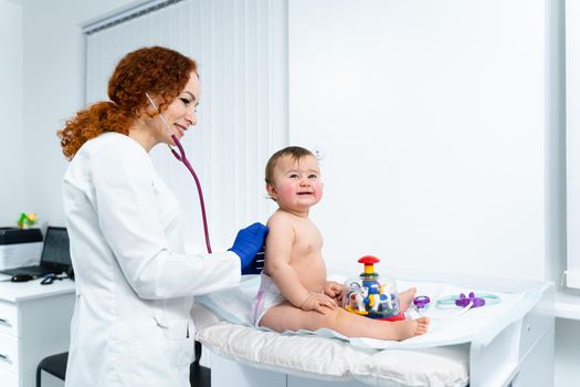 Pediatrician providing healthcare for her baby patient in the office of a specialized clinic for children. Neonatologist. Medical appointment little child one year old in the clinic. Health care of infant, children, kid.