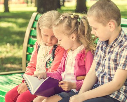 Little kids watching notes on the green bench in sunshine park