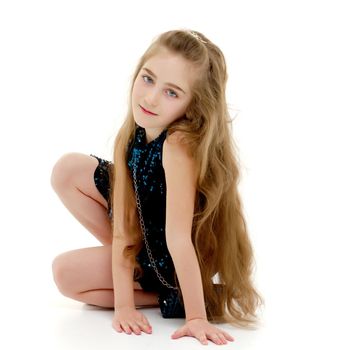 Beautiful little girl is sitting on the floor in the studio. The concept of a happy childhood, beauty and fashion. Isolated on white background.