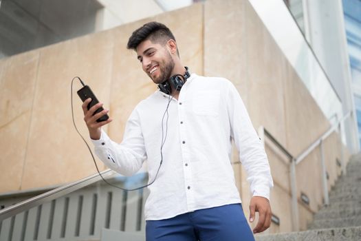 Young handsome hispanic man using smartphone outdoors. High quality photo