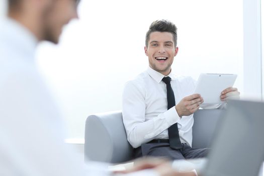 Smiling youhg businessman using laptop at desk in office