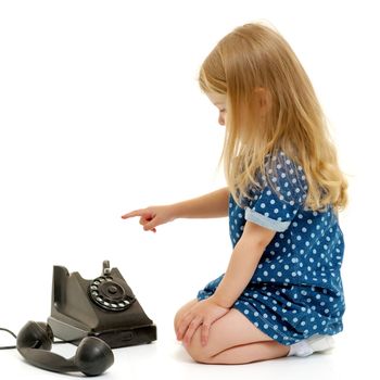Cute little girl playing with an old phone. Concept retro, nostalgia. Isolated on white background.