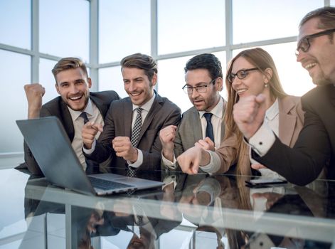 Happy young businesspeople in suit looking at laptop, excited by good news on internet