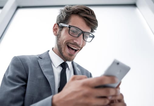Young businessman looking at mobile phone standing in the office.