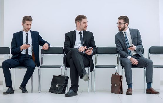 employees with smartphones sitting in the office hallway.photo with copy space