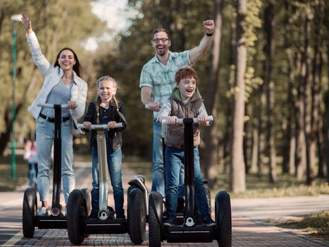 happy family riding electric scooters in the Park . The family concept. We go together.