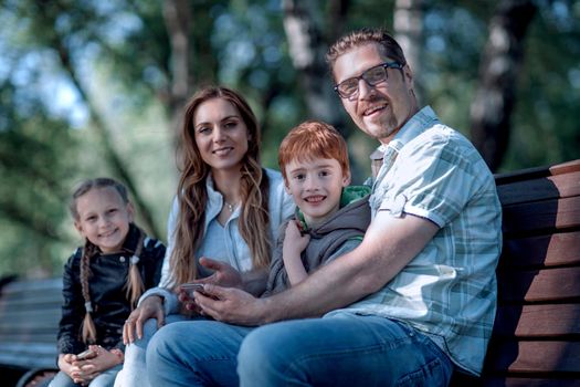 happy family sitting on bench in summer Park.the concept of family entertainment