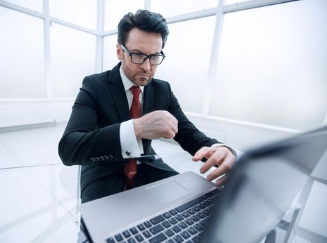 close up.serious businessman checking accounts while sitting at his Desk.business concept