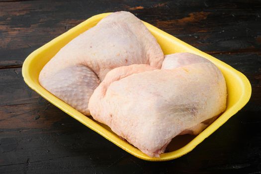 Raw fresh chicken thight or leg set, in Foam Tray Pack, on old dark wooden table