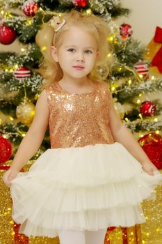 Beautiful little girl near the Christmas tree. The concept of family holidays, children's emotions.