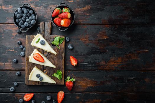 New York cheesecake or classic cheesecake with fresh berrie, on old dark wooden table background, top view flat lay with copy space for text