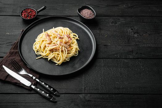 Pasta with egg sauce and ham set, on black wooden background, with copy space for text