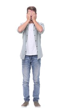 in full growth.young man covering his face with his hands.isolated on white background