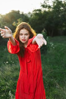 attractive woman in red dress posing in nature green grass. High quality photo