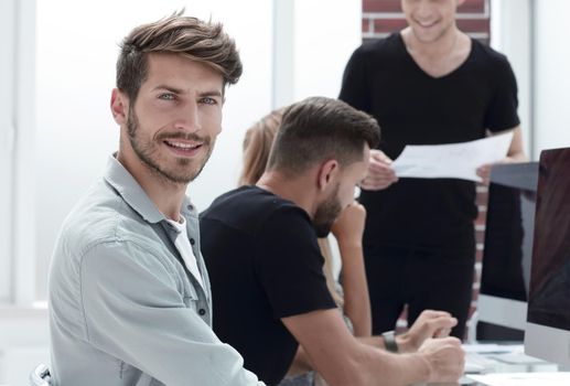 Handsome young men wearing sitting with some of his co-workers in a meeting room