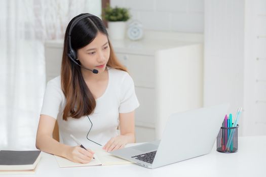 Young asian woman wearing headphone study online with e-learning on desk, girl wearing headset learning to internet with laptop computer at home, new normal, distance education and training.